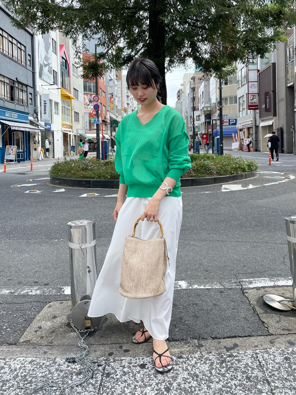 グリーン系のニット/セーター、ホワイト系のスカート、ベージュ系のバッグを着用したレディースの春コーディネートの2枚目の写真