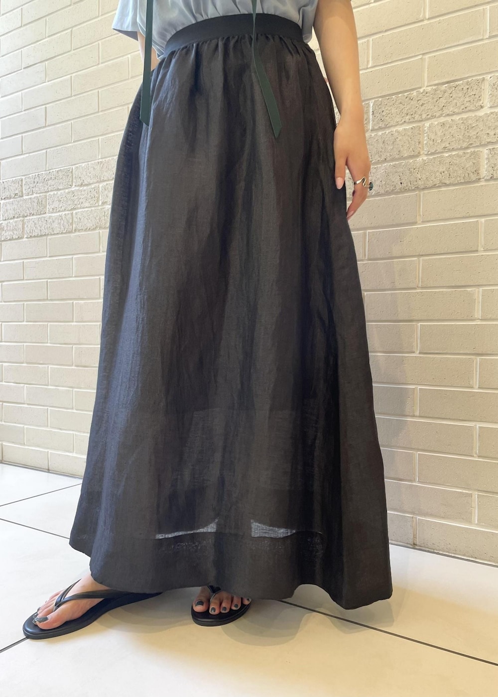 ベージュ系のサンダル、ブルー系のTシャツ/カットソー、ブラック系のスカートを着用したレディースの夏コーディネートの6枚目の写真