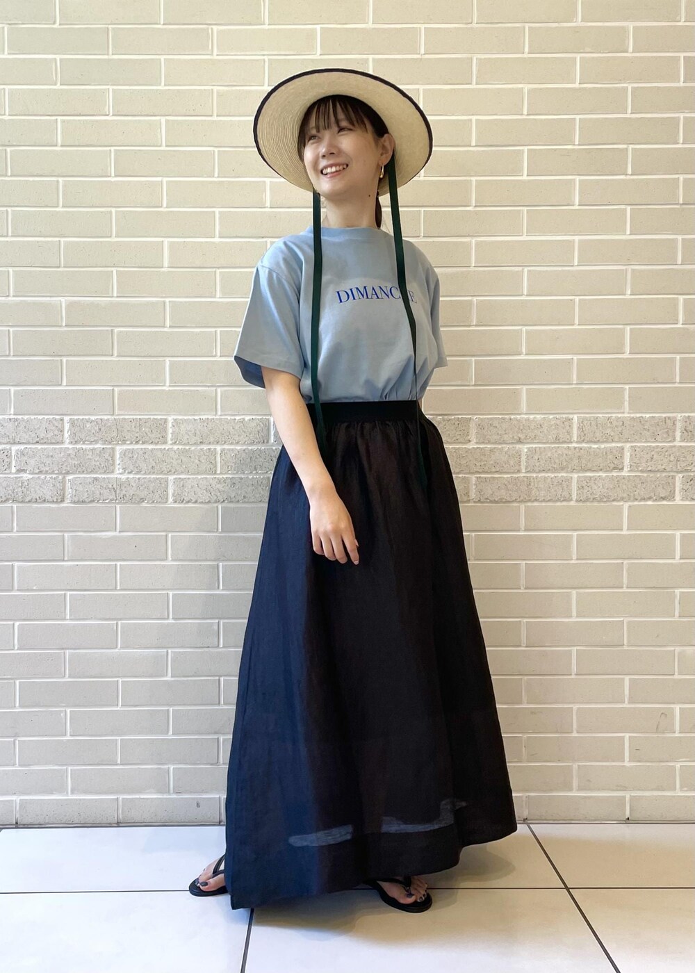 ベージュ系のサンダル、ブルー系のTシャツ/カットソー、ブラック系のスカートを着用したレディースの夏コーディネートの2枚目の写真