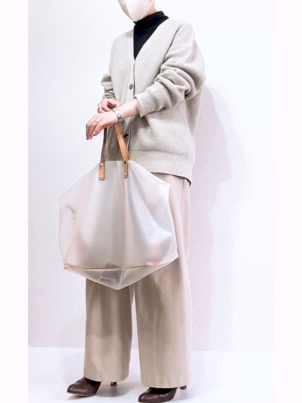 ホワイト系のバッグ、グリーン系のカーディガン/ボレロ、ブラック系のニット/セーターを着用したレディースの冬コーディネートの2枚目の写真