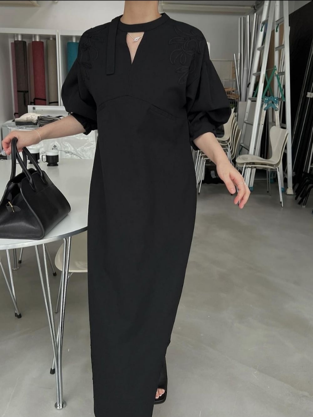 ブラック系のワンピース、ブラック系のハンドバッグを着用したレディースの夏コーディネートの2枚目の写真