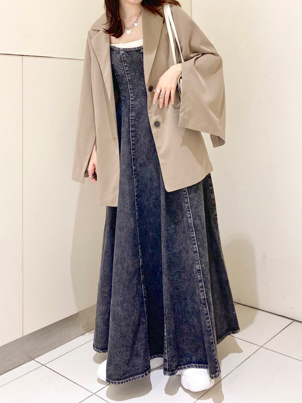 ブラック系のワンピース、ベージュ系のテーラードジャケット、ホワイト系のキャミソールを着用したレディースの春コーディネートの3枚目の写真