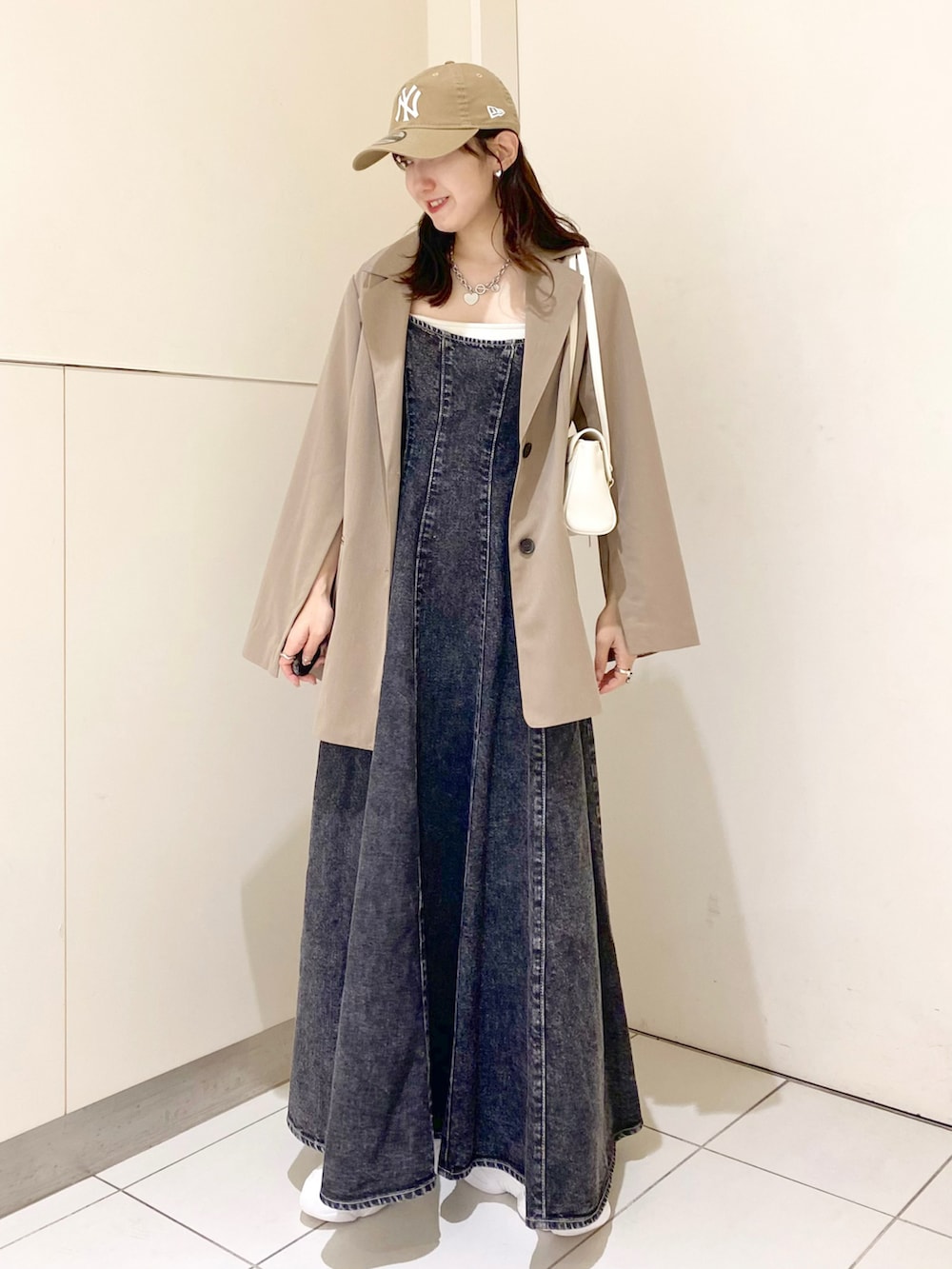 ブラック系のワンピース、ベージュ系のテーラードジャケット、ホワイト系のキャミソールを着用したレディースの春コーディネートの2枚目の写真