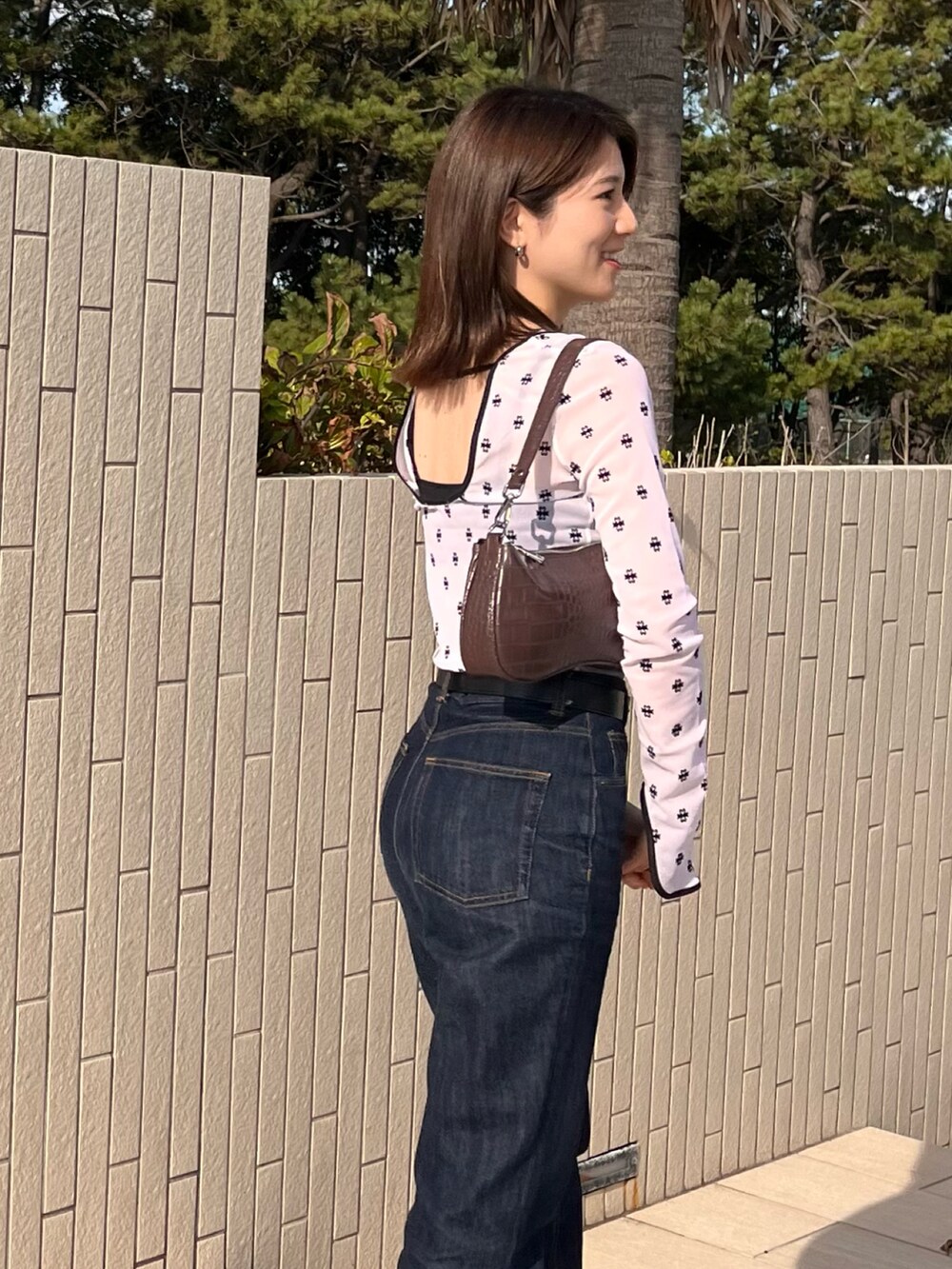 ブルー系のデニムパンツ、ブラック系のシューズ、ホワイト系のTシャツ/カットソーを着用したレディースの秋コーディネートの2枚目の写真