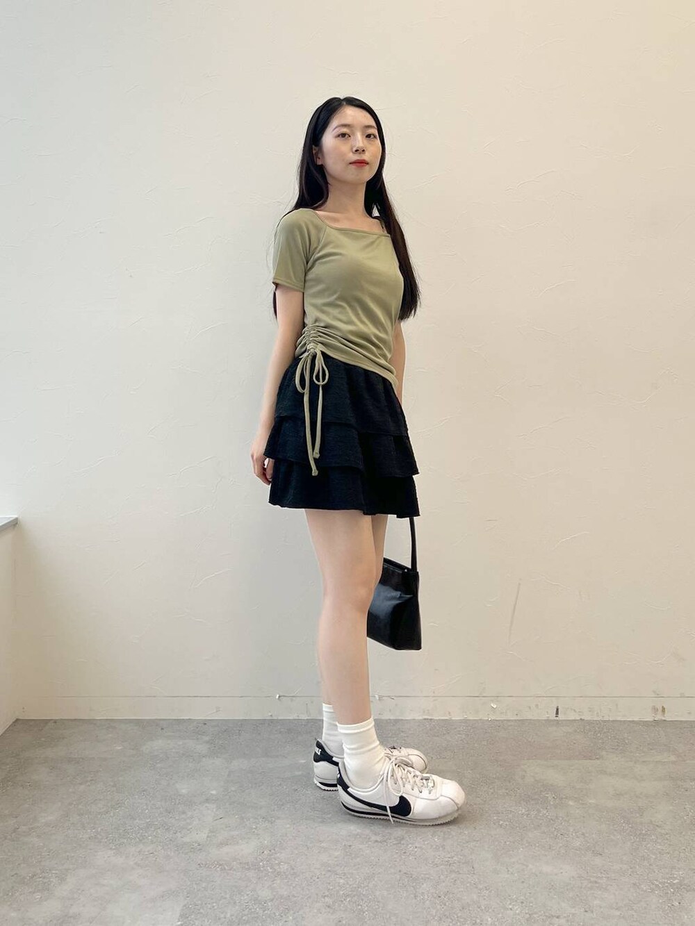 グリーン系のTシャツ/カットソー、ブラック系のハンドバッグ、ブラック系のスカートを着用したレディースの夏コーディネートの4枚目の写真
