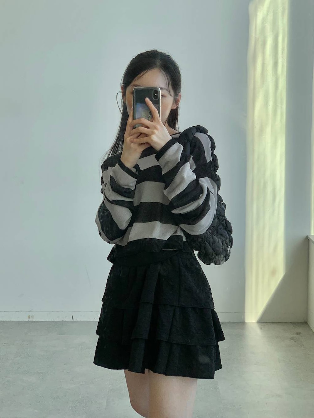 ブラック系のショルダーバッグ、ブラック系のスカート、ブラック系のニット/セーターを着用したレディースの秋コーディネートの9枚目の写真