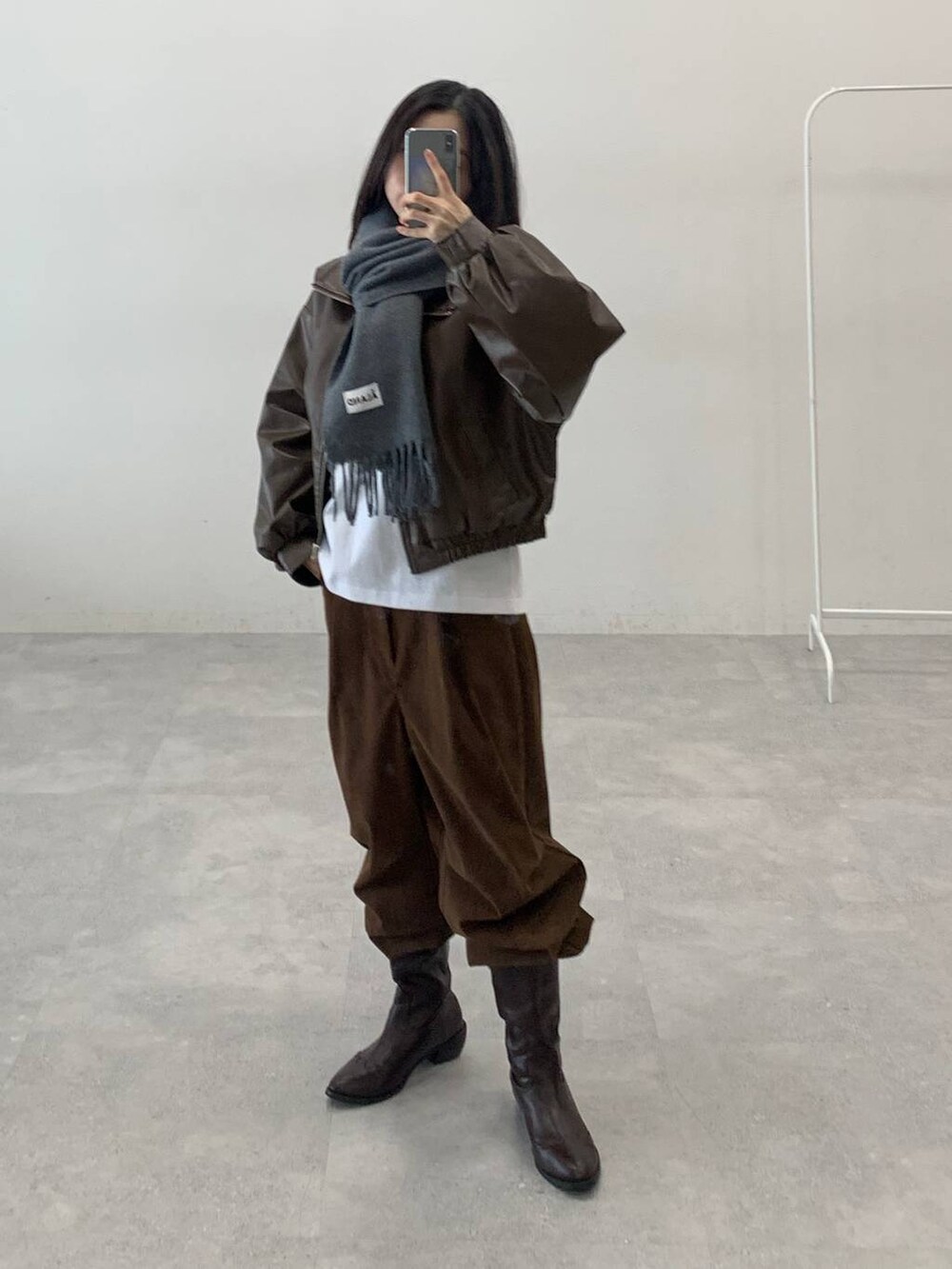 ブラウン系のブルゾン、ブラウン系のその他パンツ、グレー系のマフラーを着用したレディースの秋コーディネートの2枚目の写真