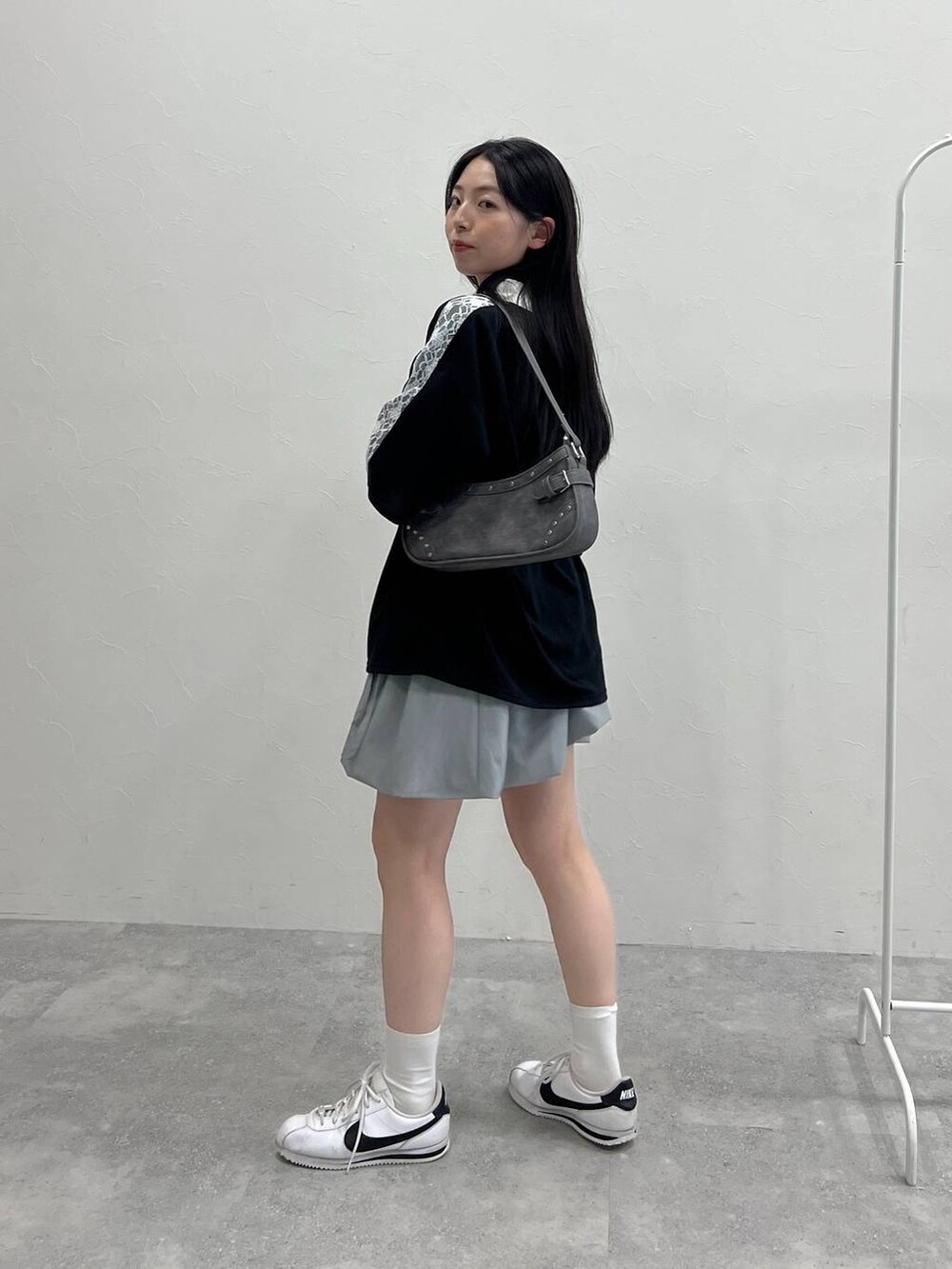 グレー系のスカート、ブラック系のトートバッグ、ブラック系のTシャツ/カットソーを着用したレディースの夏コーディネートの3枚目の写真