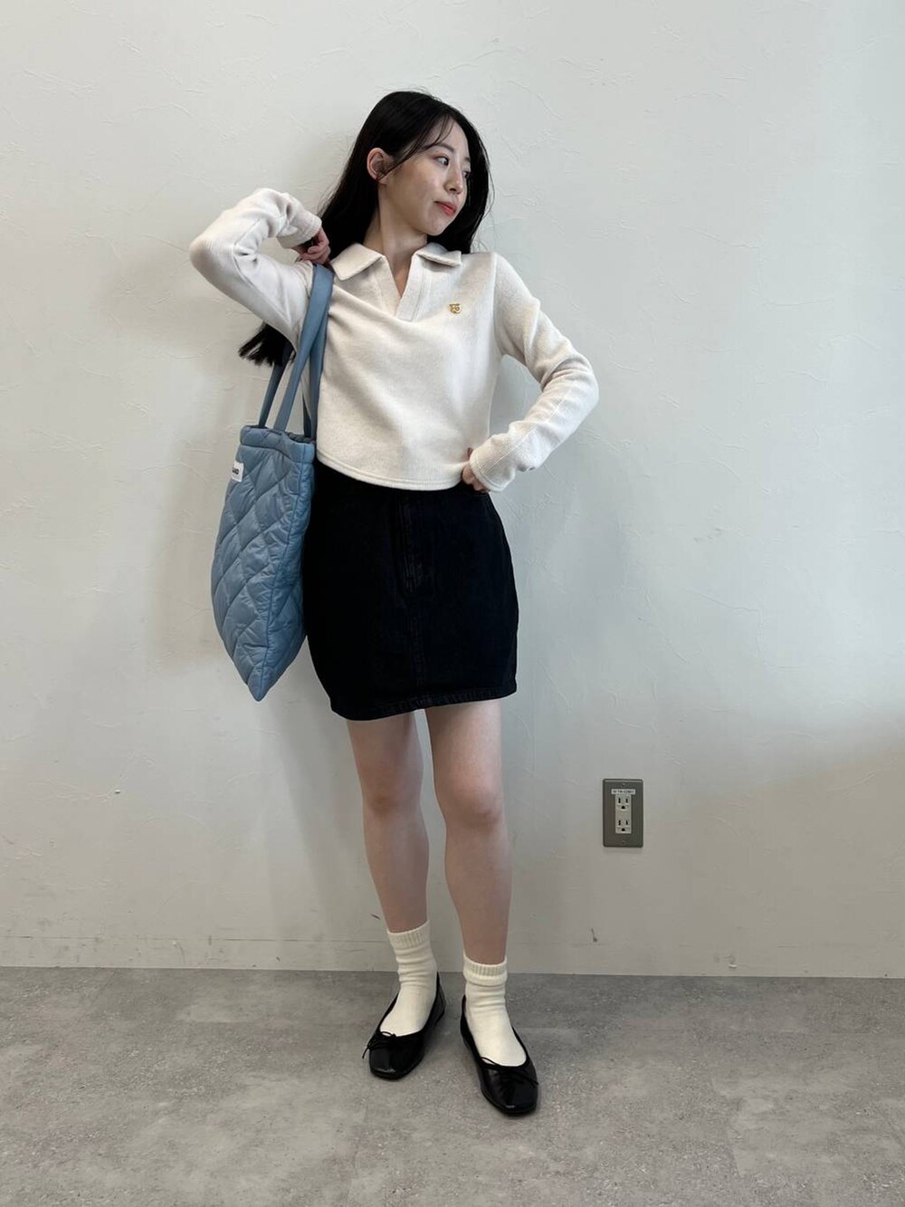 ブラック系のデニムスカート、ブラック系のバレエシューズ、ブルー系のトートバッグを着用したレディースの冬コーディネートの4枚目の写真