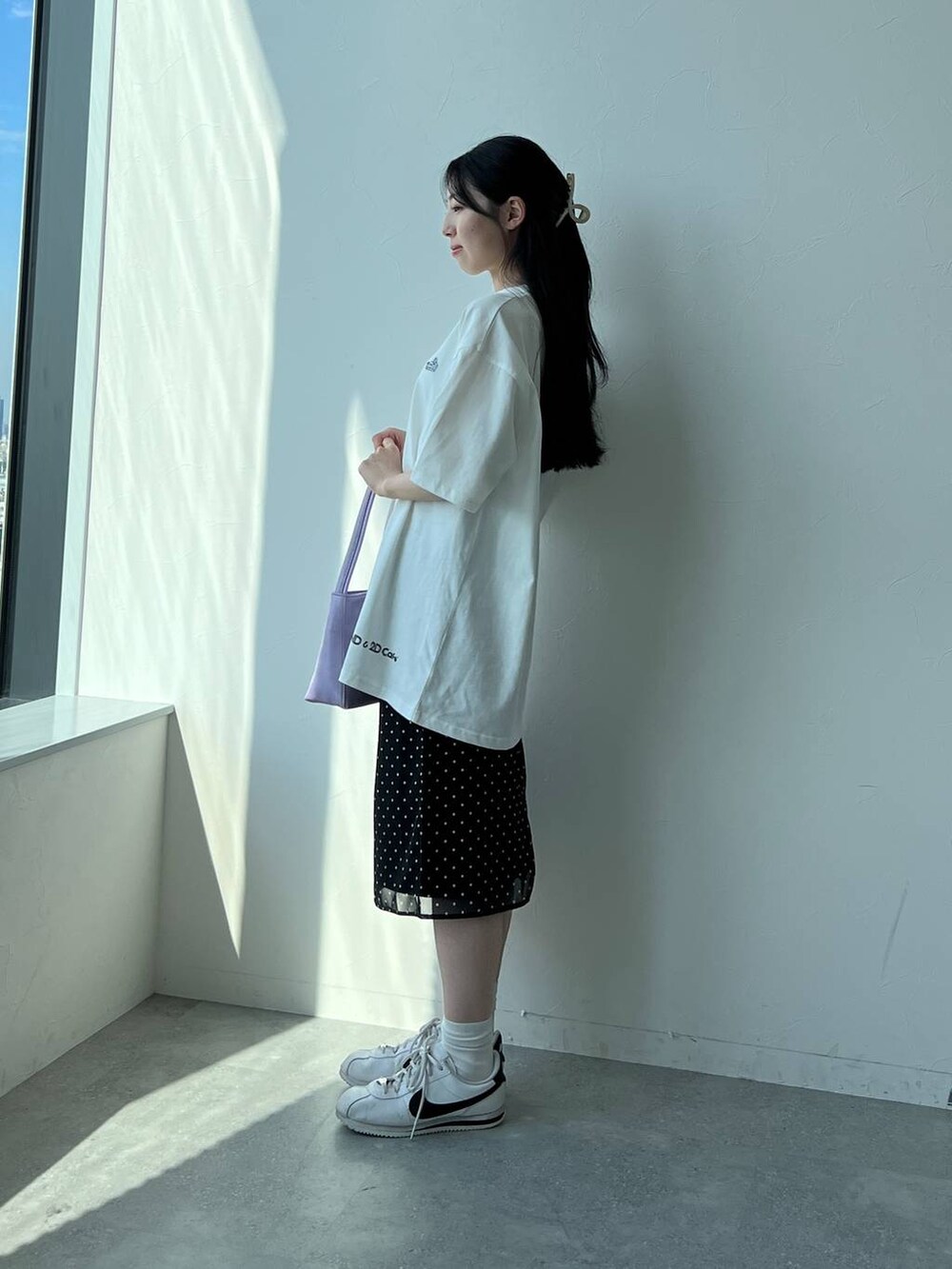 ブラック系のスカート、パープル系のハンドバッグ、ホワイト系のTシャツ/カットソーを着用したレディースの夏コーディネートの3枚目の写真