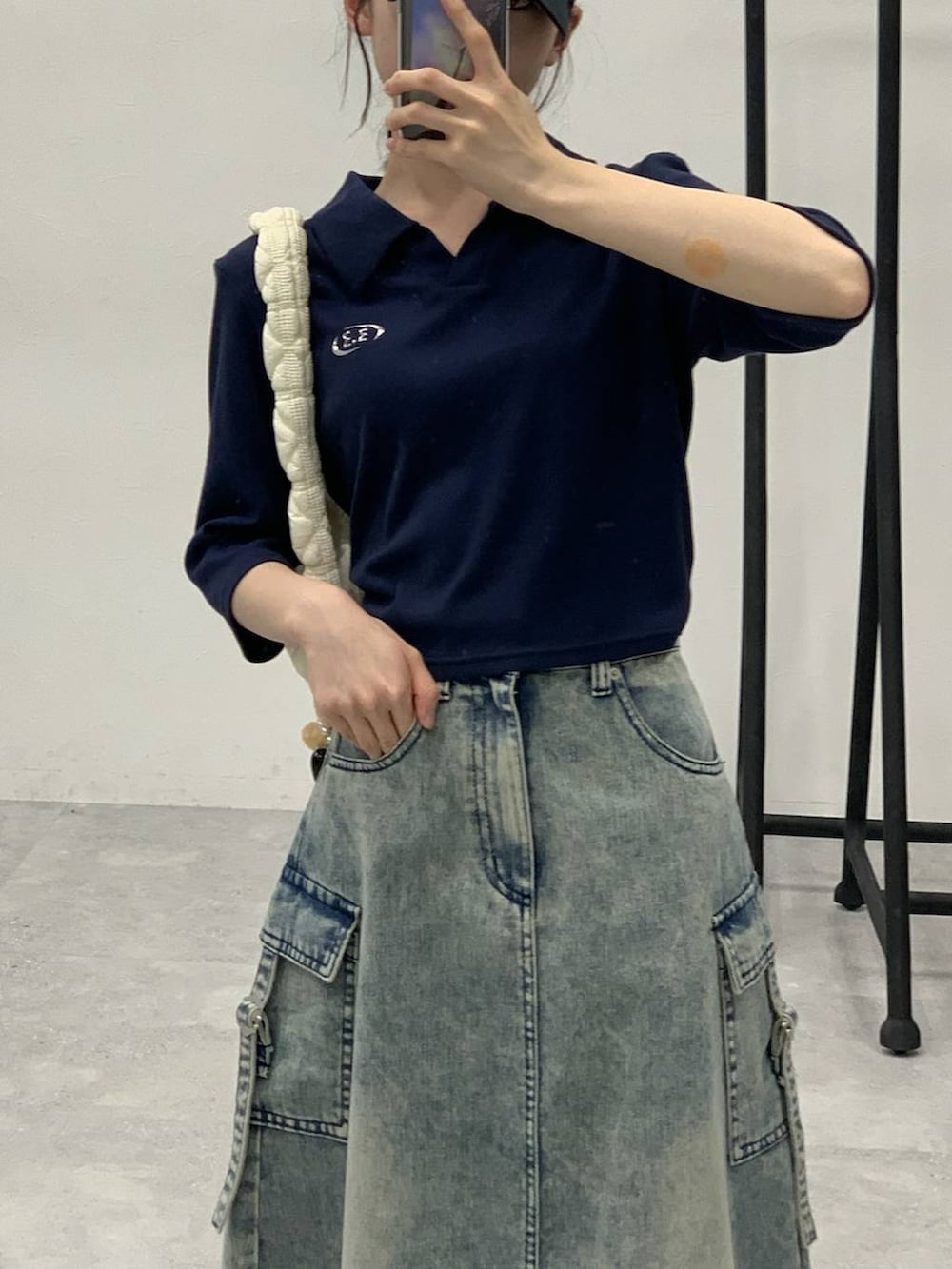 ブルー系のデニムスカート、ホワイト系のショルダーバッグ、ブルー系のTシャツ/カットソーを着用したレディースの秋コーディネートの5枚目の写真