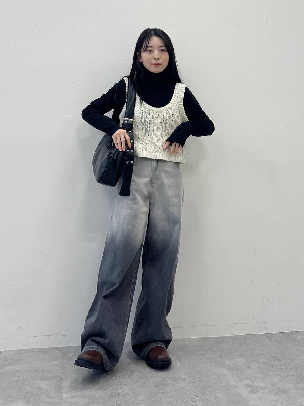 ブラック系のショルダーバッグ、ブラック系のデニムパンツ、ベージュ系のベストを着用したレディースの冬コーディネートの6枚目の写真