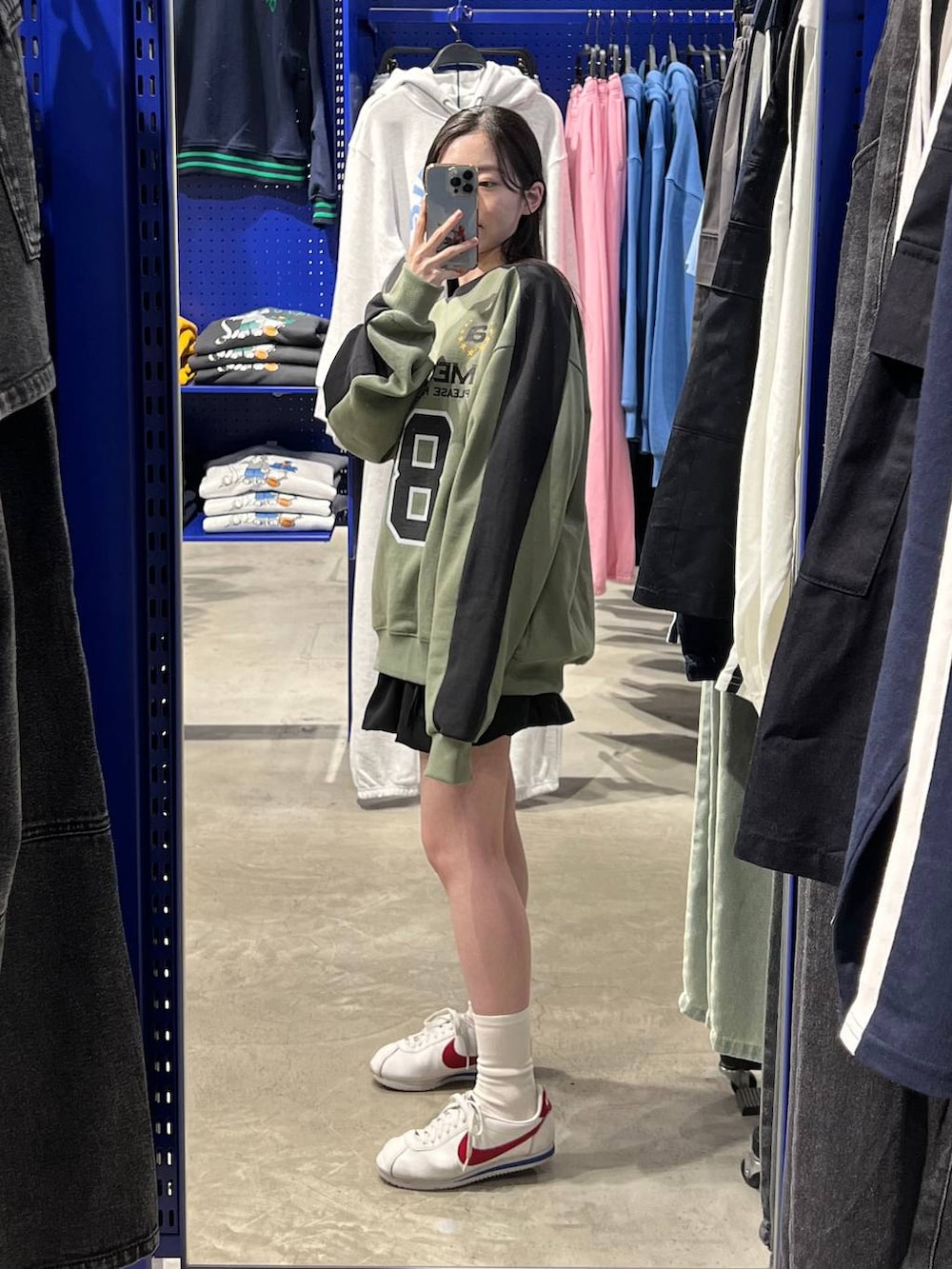 ブラック系のスカート、グリーン系のスウェットを着用したレディースの春コーディネートの2枚目の写真