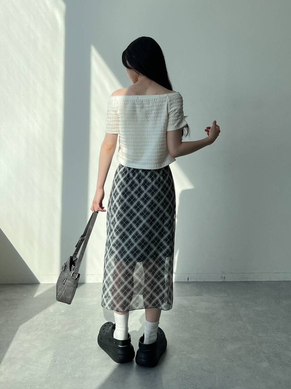 ホワイト系のTシャツ/カットソー、グレー系のスカート、ブラック系のトートバッグを着用したレディースの夏コーディネートの4枚目の写真