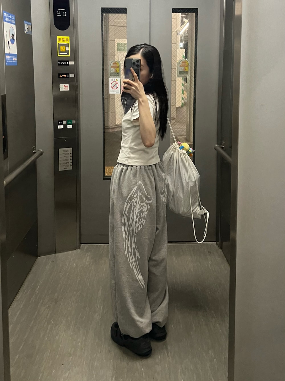 ホワイト系のTシャツ/カットソー、グレー系のスウェットパンツ、ブラック系のスニーカーを着用したレディースの秋コーディネートの2枚目の写真