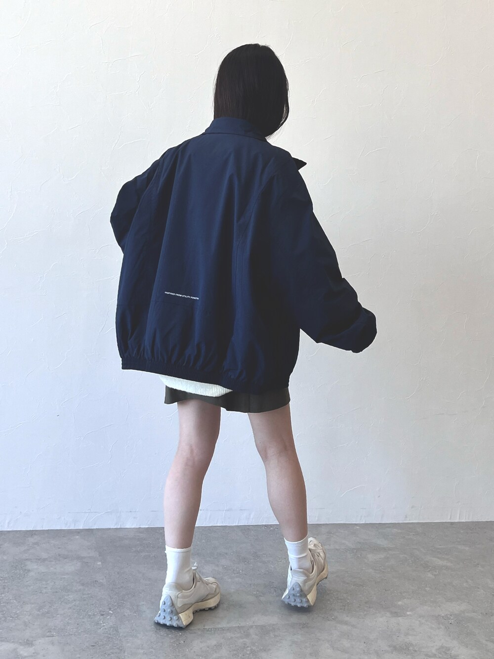 グリーン系のスカート、ホワイト系のスニーカー、ブルー系のナイロンジャケットを着用したレディースの冬コーディネートの2枚目の写真