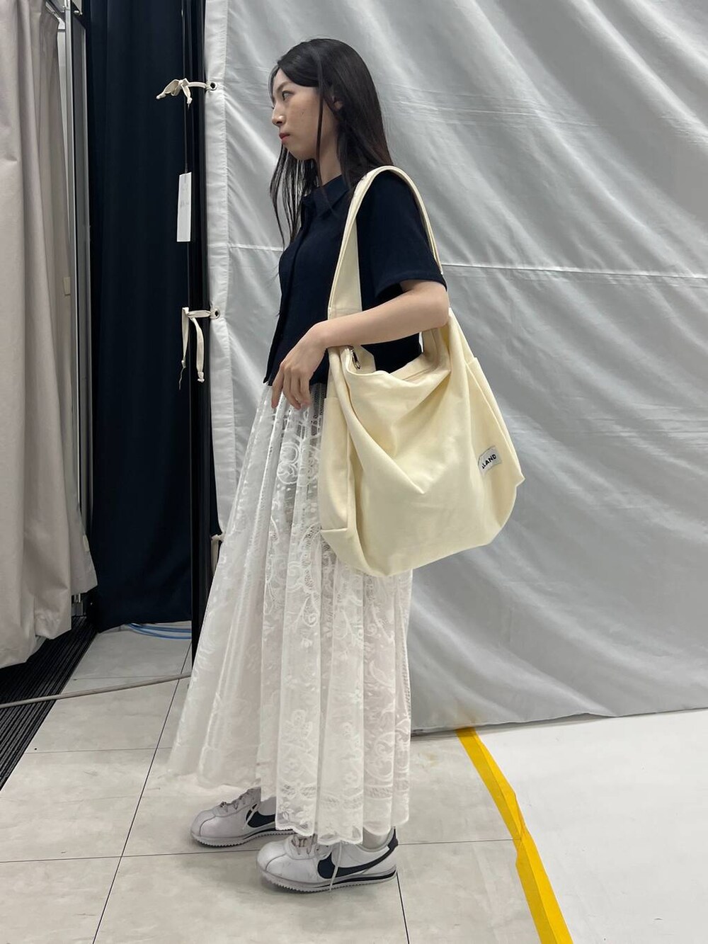 ホワイト系のスカート、ベージュ系のショルダーバッグ、グレー系のデニムパンツを着用したレディースの夏コーディネートの3枚目の写真