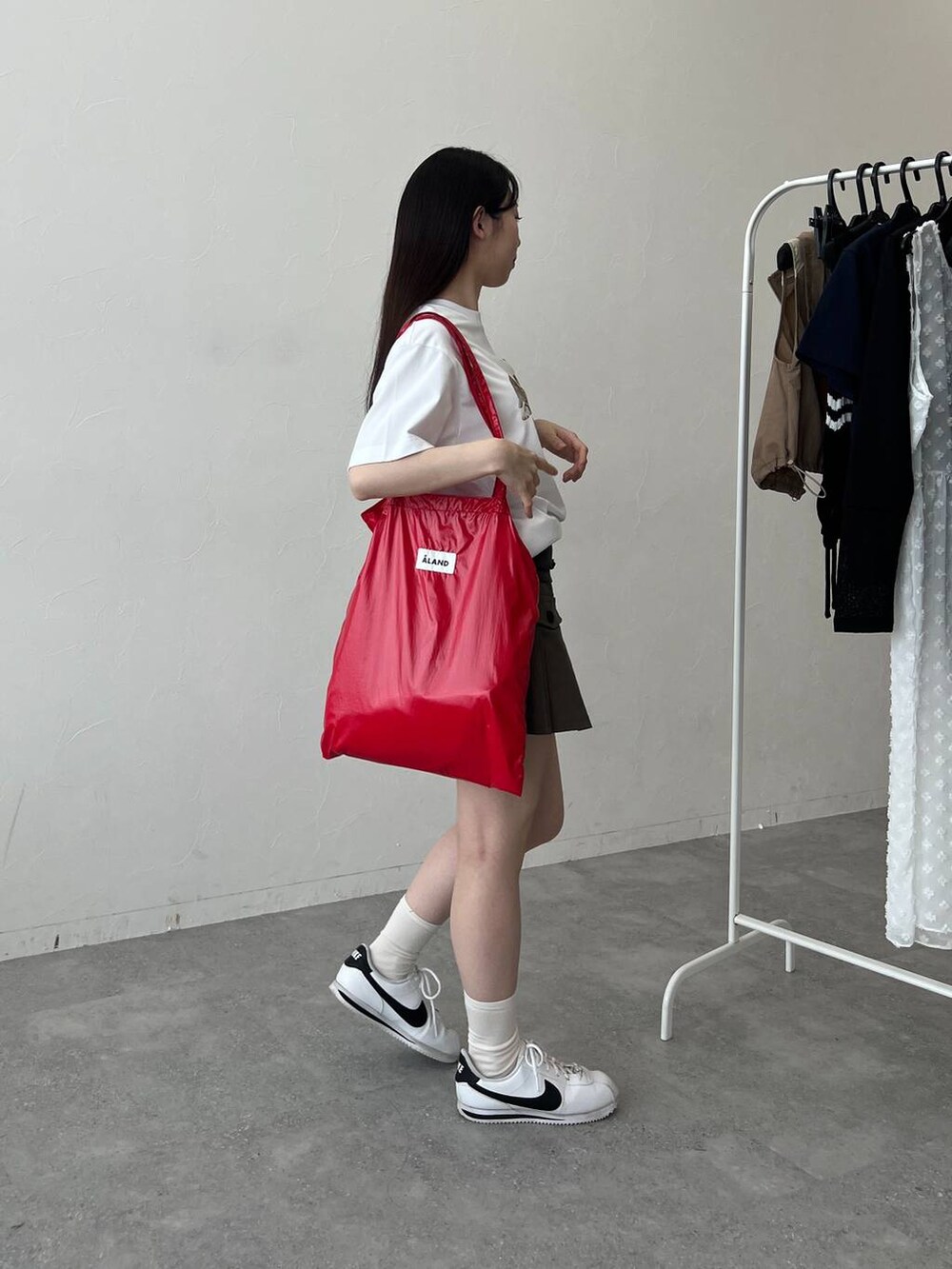 レッド系のトートバッグ、ホワイト系のTシャツ/カットソーを着用したレディースの春コーディネートの3枚目の写真