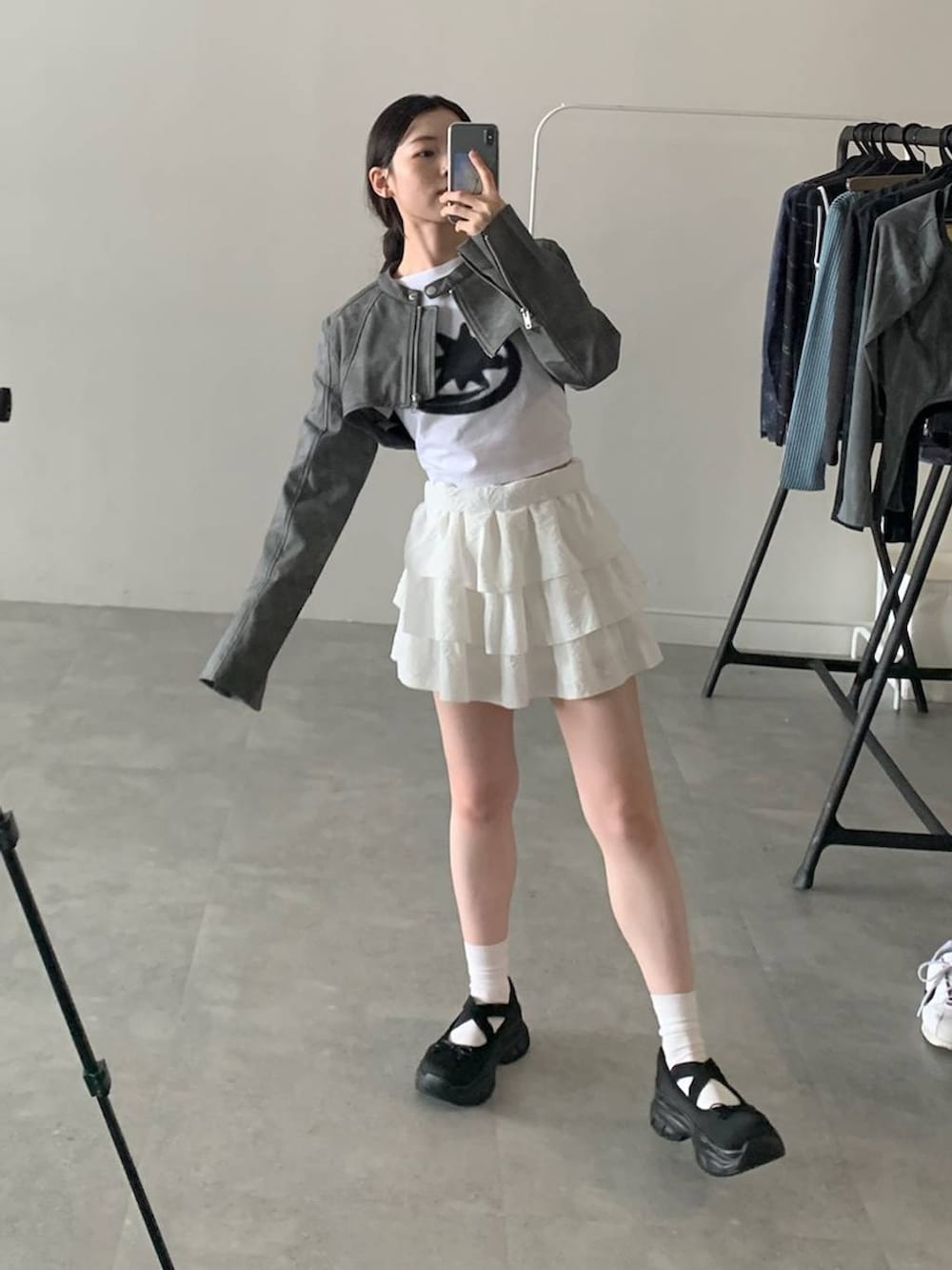 グレー系のライダースジャケット、ホワイト系のスカート、ホワイト系のTシャツ/カットソーを着用したレディースの秋コーディネートの2枚目の写真