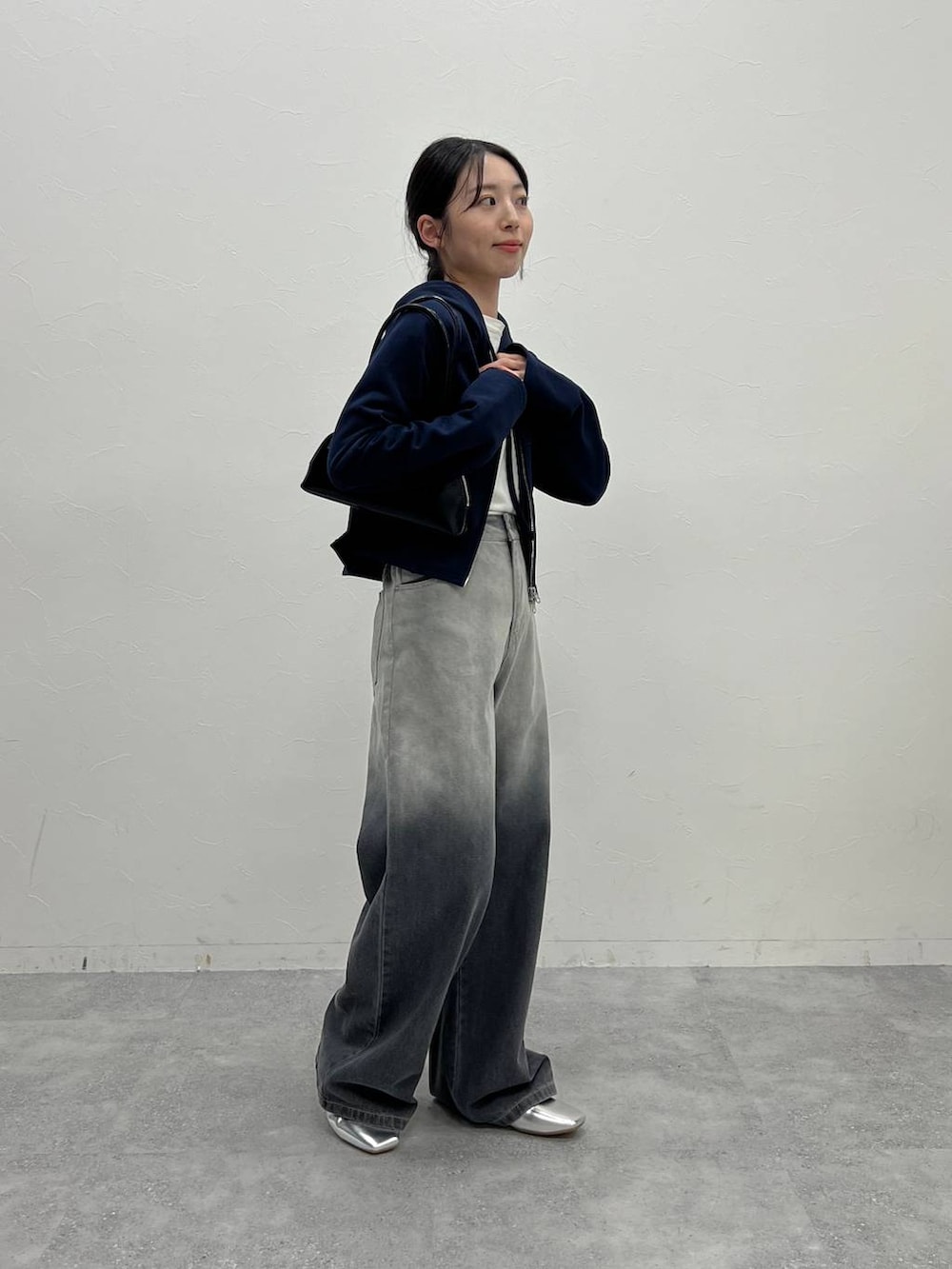 ブルー系のスウェット、ブラック系のデニムパンツ、ブラック系のハンドバッグを着用したレディースの冬コーディネートの3枚目の写真