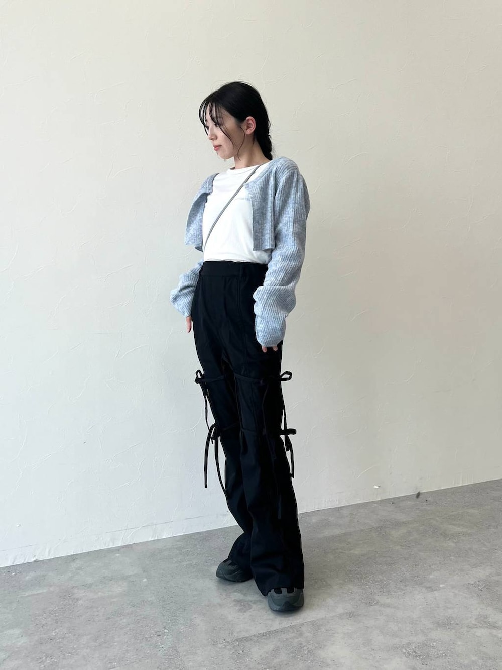 グレー系のショルダーバッグ、ベージュ系のTシャツ/カットソー、ブラック系のスラックスを着用したレディースの冬コーディネートの3枚目の写真