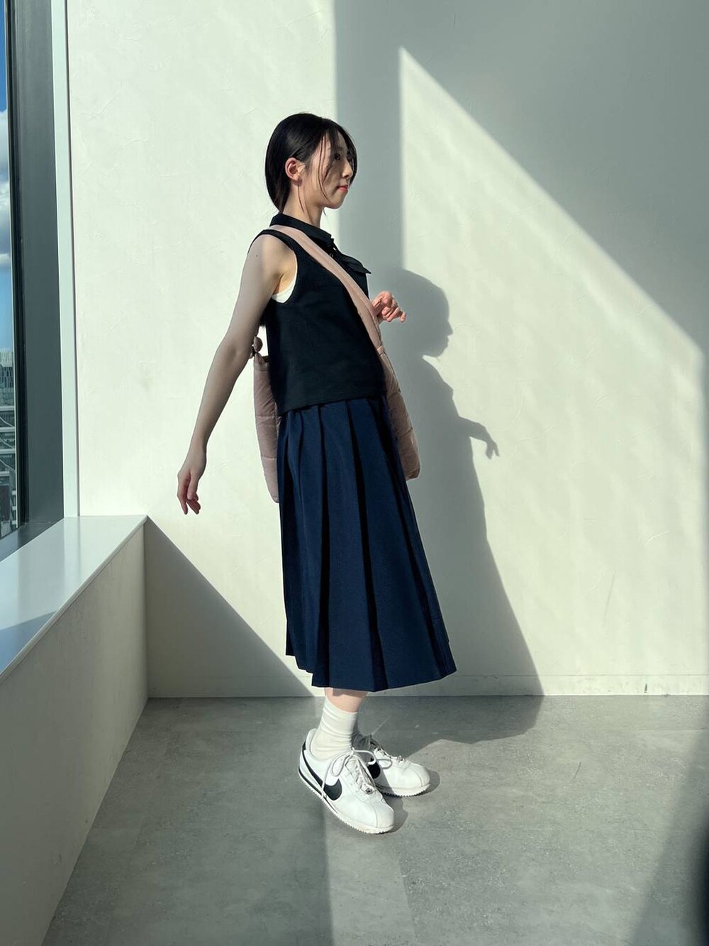 ブルー系のスカート、ピンク系のショルダーバッグ、ブラック系のタンクトップを着用したレディースの夏コーディネートの3枚目の写真