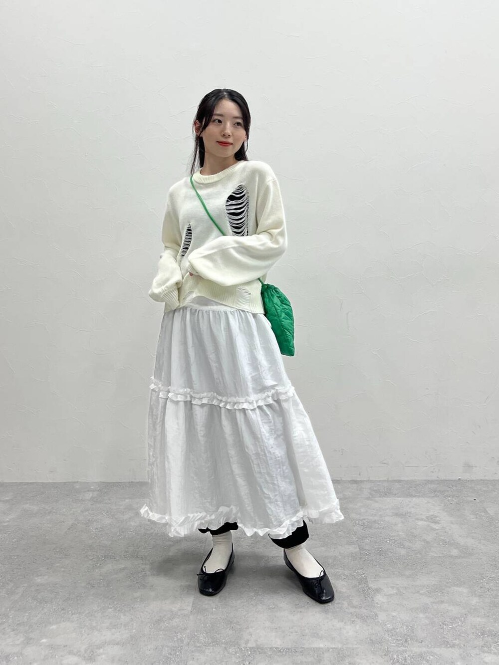 ホワイト系のニット/セーター、グリーン系のショルダーバッグ、ブラック系のスウェットパンツを着用したレディースの春コーディネートの6枚目の写真