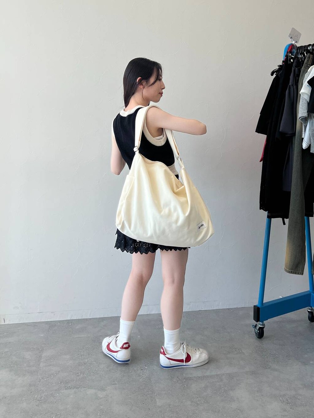 ブラック系のスカート、ブラック系のベスト、ベージュ系のショルダーバッグを着用したレディースの春コーディネートの4枚目の写真