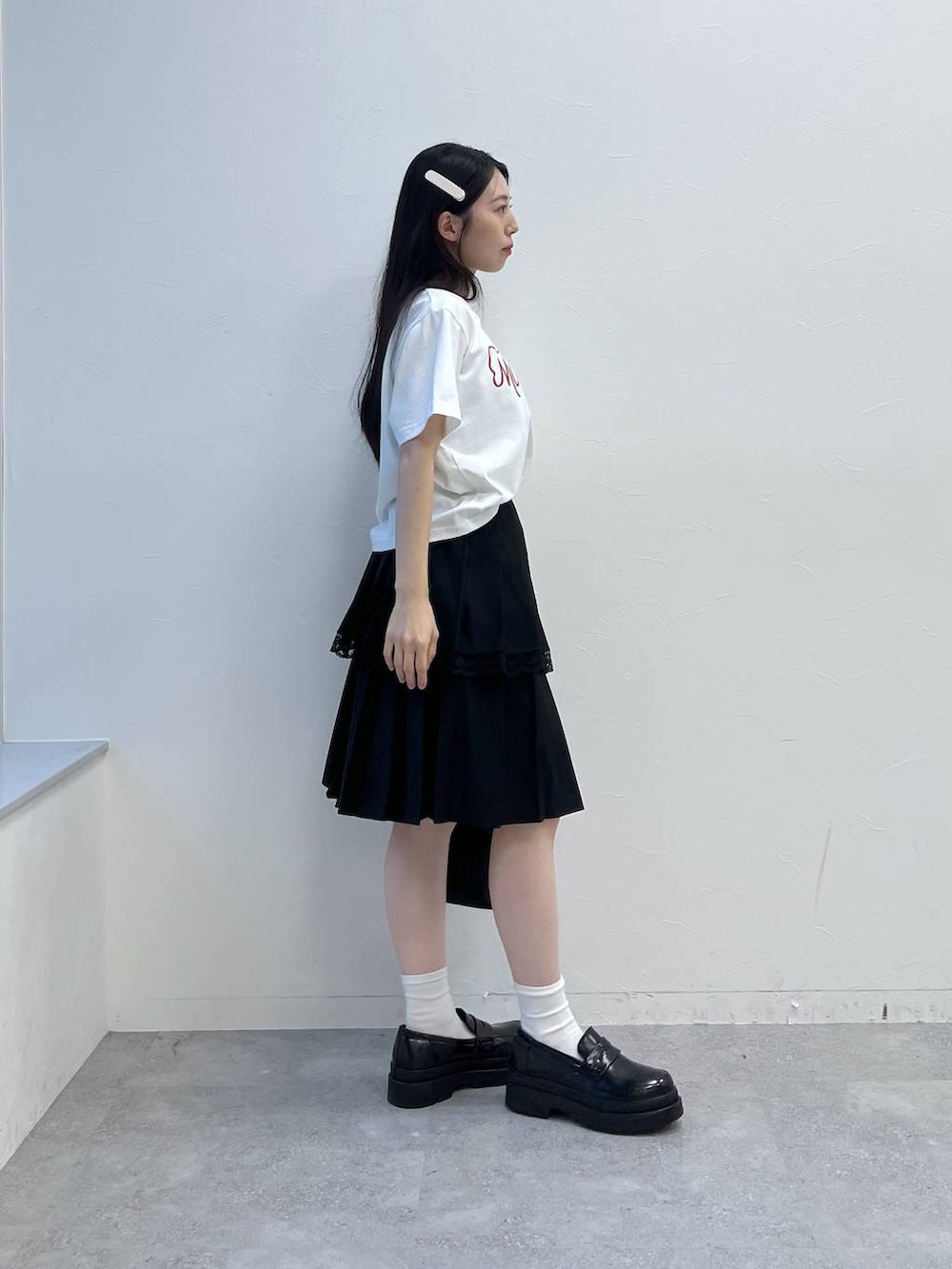 ブラック系のスカート、ホワイト系のTシャツ/カットソー、ブラック系のハンドバッグを着用したレディースの夏コーディネートの5枚目の写真
