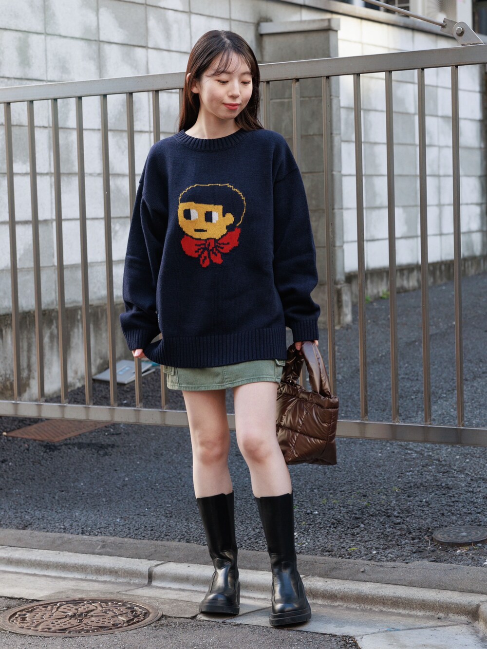 ブラック系のブーツ、ブラウン系のハンドバッグ、グリーン系のスカートを着用したレディースの冬コーディネートの3枚目の写真