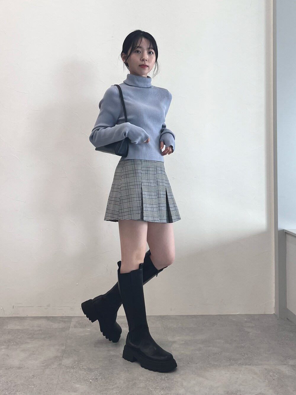 ブラック系のブーツ、グレー系のスカート、ブルー系のニット/セーターを着用したレディースの冬コーディネートの2枚目の写真