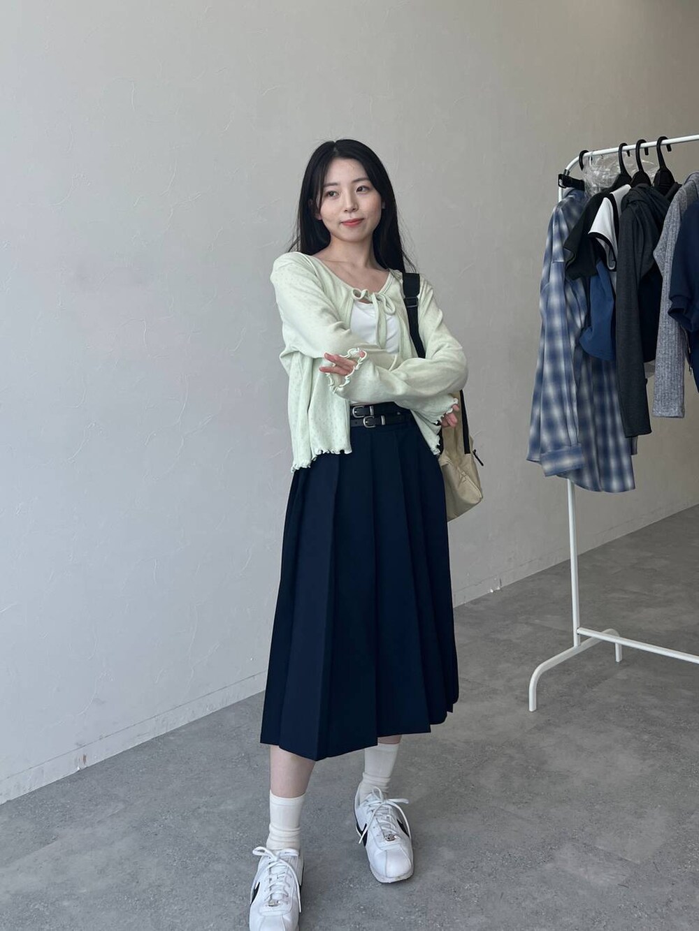 ベージュ系のバックパック/リュック、ブルー系のスカート、グリーン系のカーディガン/ボレロを着用したレディースの春コーディネートの7枚目の写真