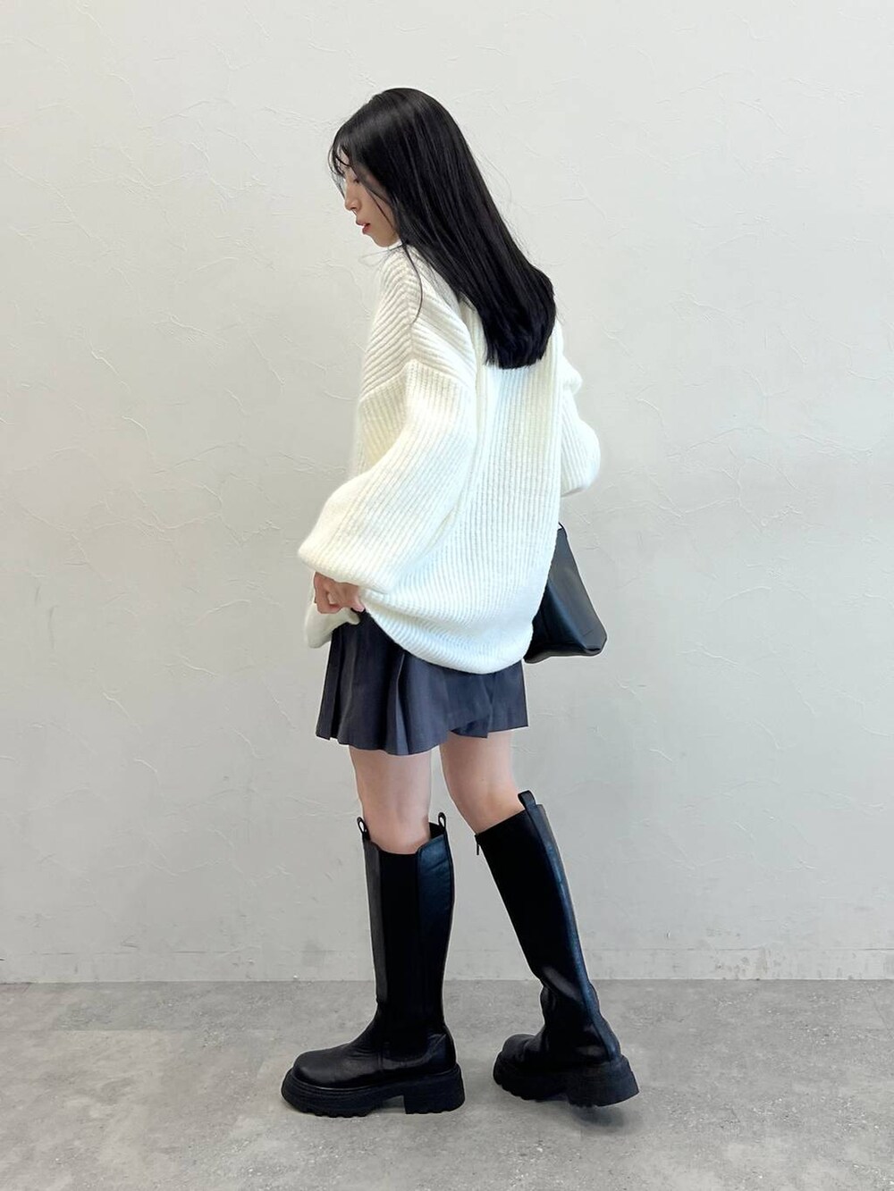 ブラック系のブーツ、ブラック系のショルダーバッグ、ホワイト系のニット/セーターを着用したレディースの冬コーディネートの3枚目の写真