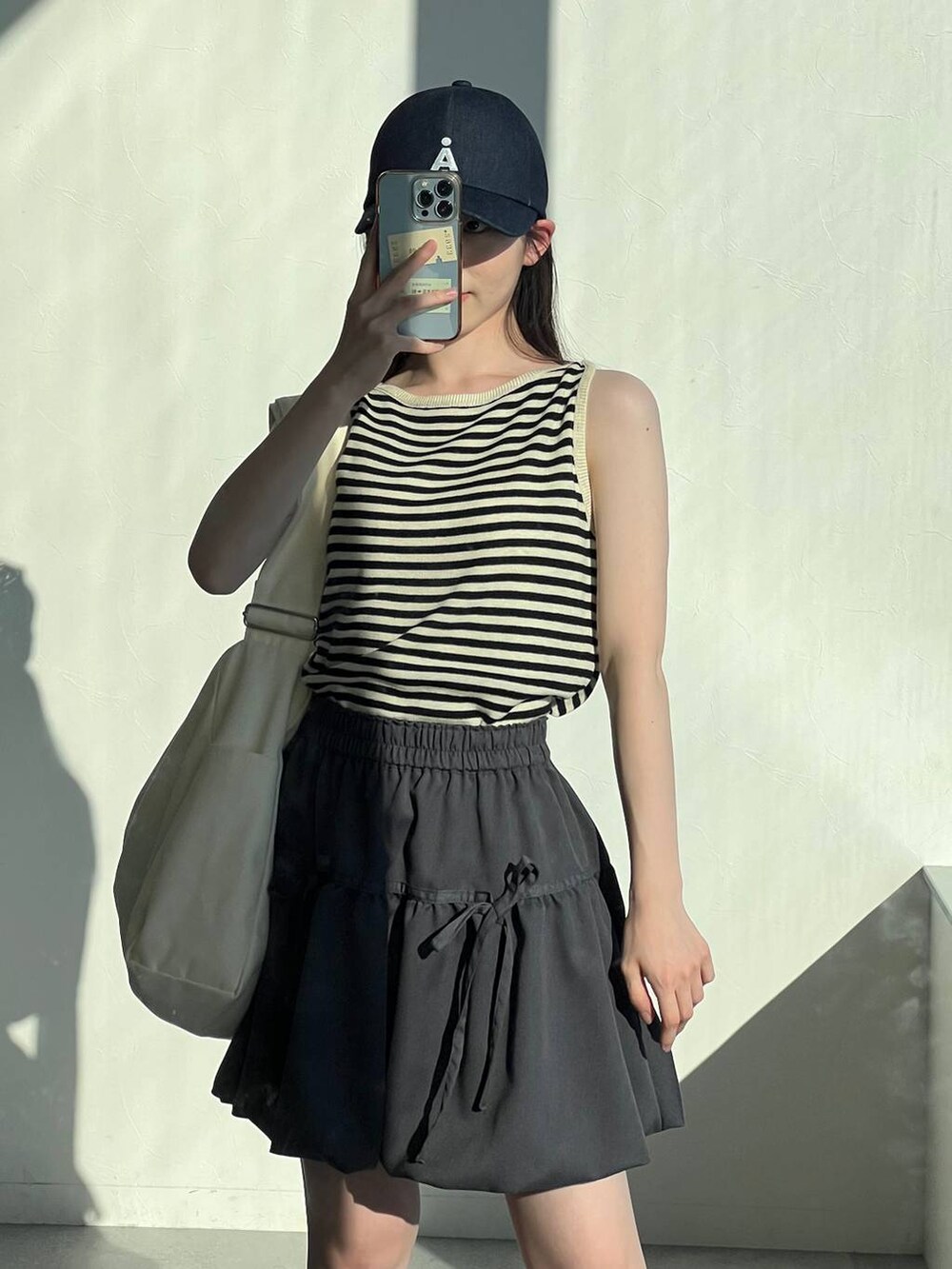 ベージュ系のTシャツ/カットソー、ベージュ系のショルダーバッグ、グレー系のスカートを着用したレディースの春コーディネートの7枚目の写真