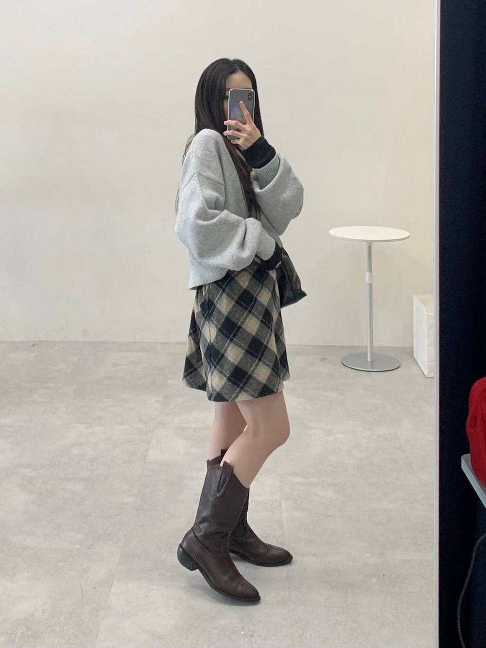 グレー系のニット/セーター、ブラック系のスカート、ブラック系のハンドバッグを着用したレディースの秋コーディネートの3枚目の写真