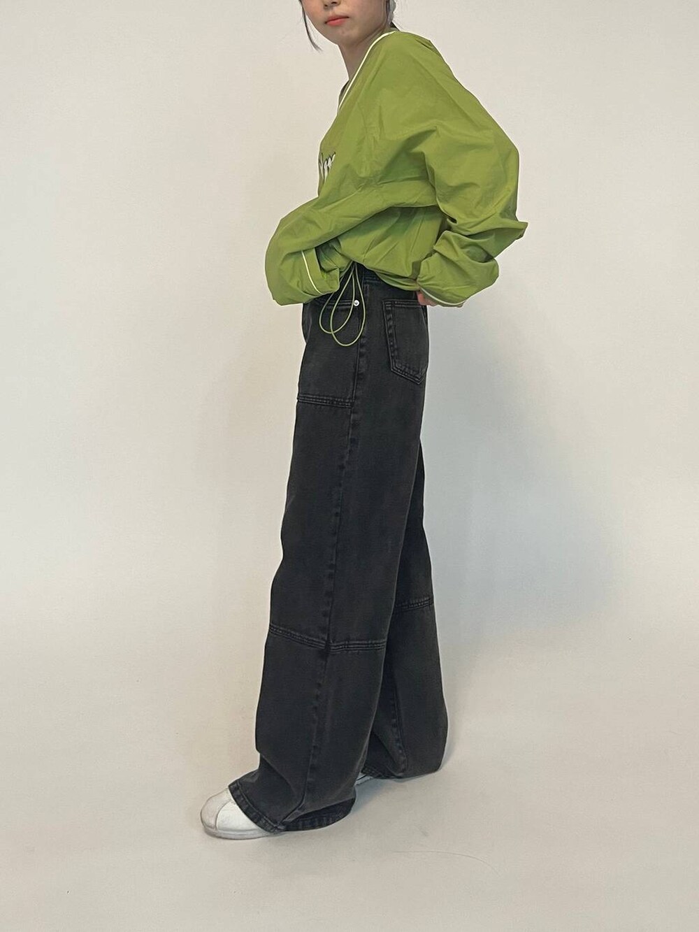 グリーン系のTシャツ/カットソー、ホワイト系のスニーカー、ブラック系のデニムパンツを着用したレディースの冬コーディネートの2枚目の写真