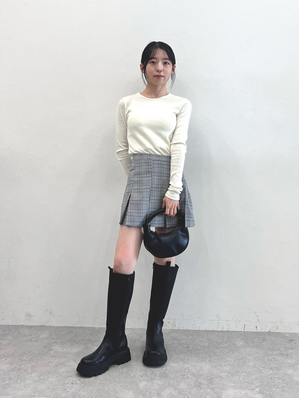 ブラック系のブーツ、ブラック系のショルダーバッグ、グレー系のスカートを着用したレディースの秋コーディネートの2枚目の写真