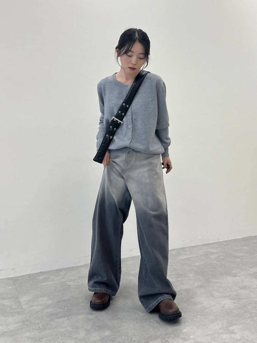 ブラック系のショルダーバッグ、ブラック系のデニムパンツ、グレー系のカーディガン/ボレロを着用したレディースの冬コーディネートの2枚目の写真
