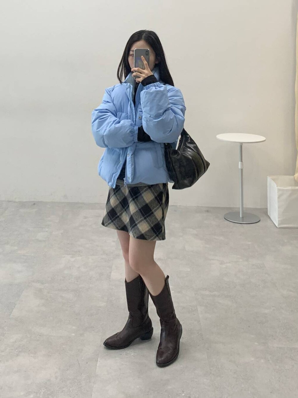 ブラック系のスカート、ブラック系のハンドバッグ、ブラック系のTシャツ/カットソーを着用したレディースの冬コーディネートの3枚目の写真