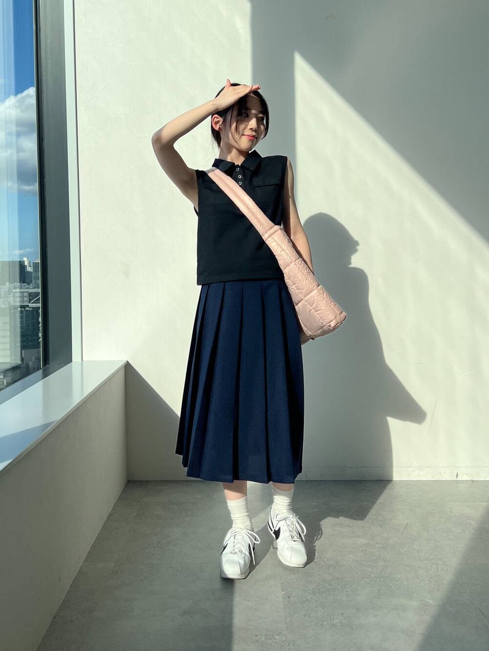 ブルー系のスカート、ピンク系のショルダーバッグ、ブラック系のタンクトップを着用したレディースの夏コーディネートの2枚目の写真