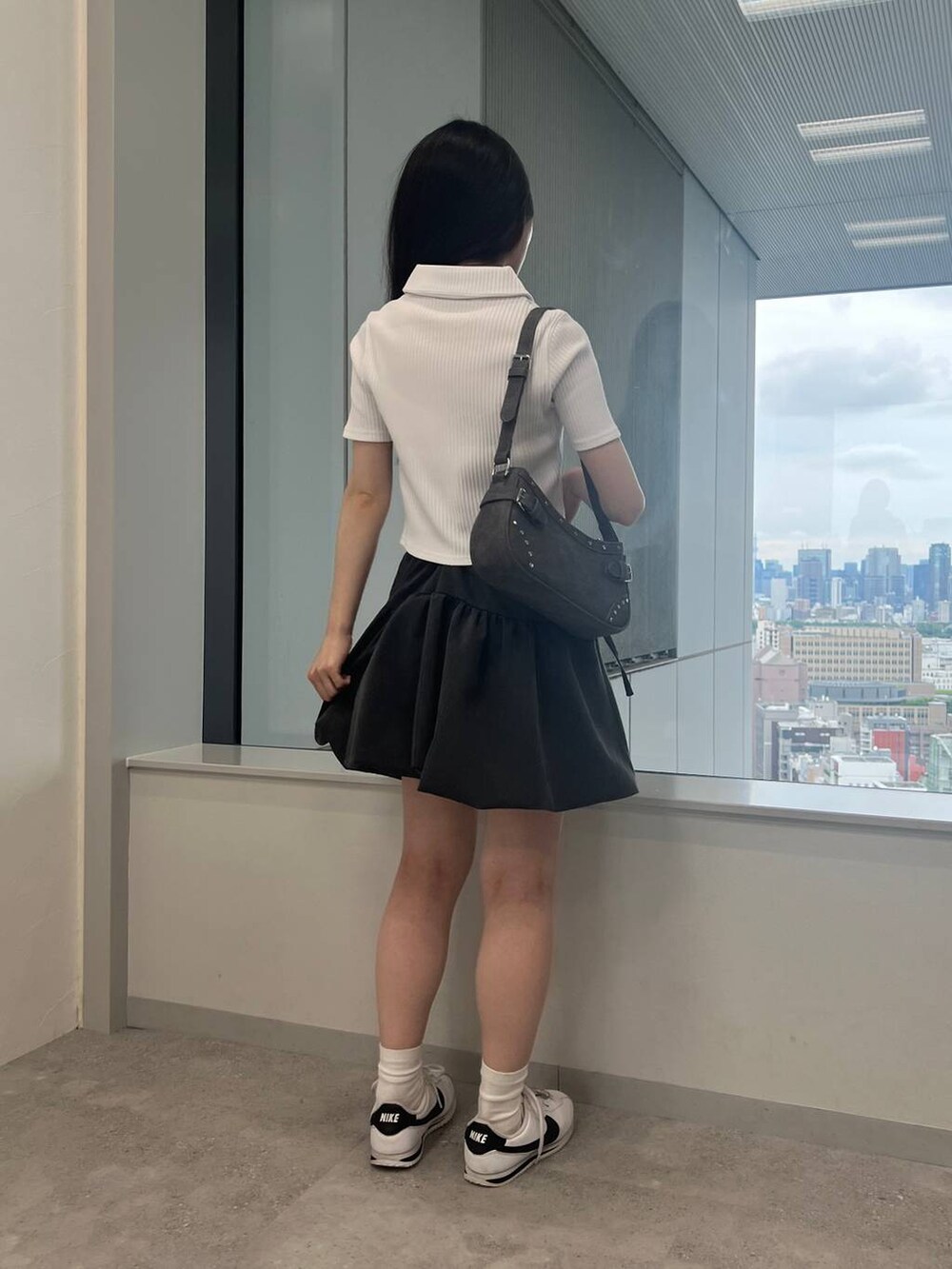 グレー系のスカート、ブラック系のトートバッグ、ホワイト系のカーディガン/ボレロを着用したレディースの夏コーディネートの2枚目の写真