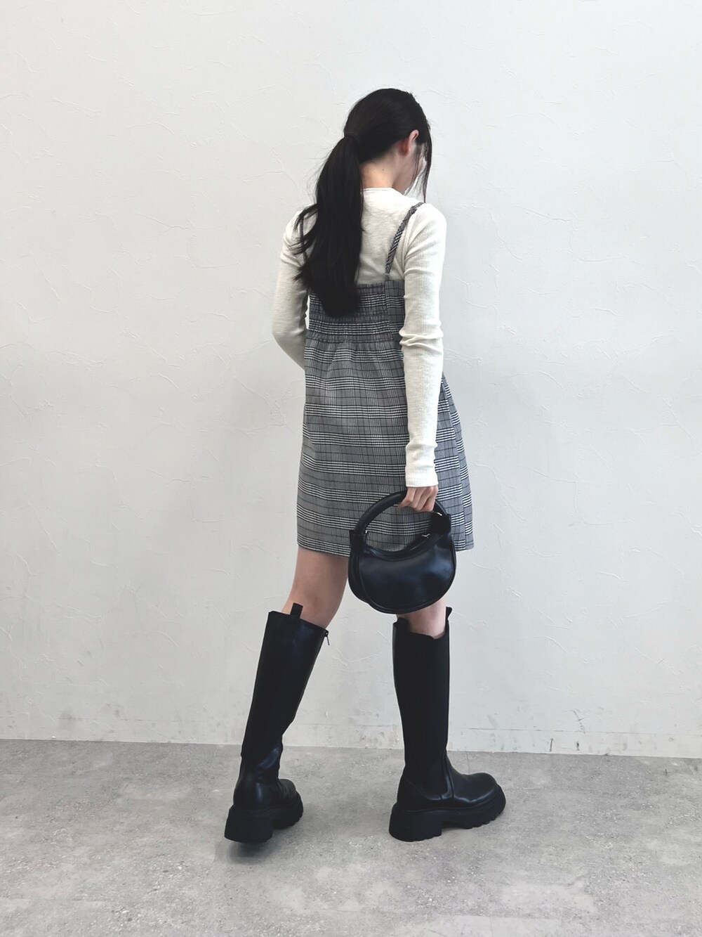 ブラック系のブーツ、ブラック系のショルダーバッグ、グレー系のスカートを着用したレディースの秋コーディネートの4枚目の写真