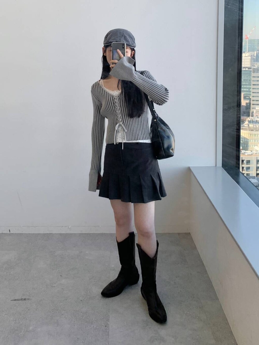 グレー系のカーディガン/ボレロ、グレー系のスカート、ブラック系のハンドバッグを着用したレディースの冬コーディネートの2枚目の写真