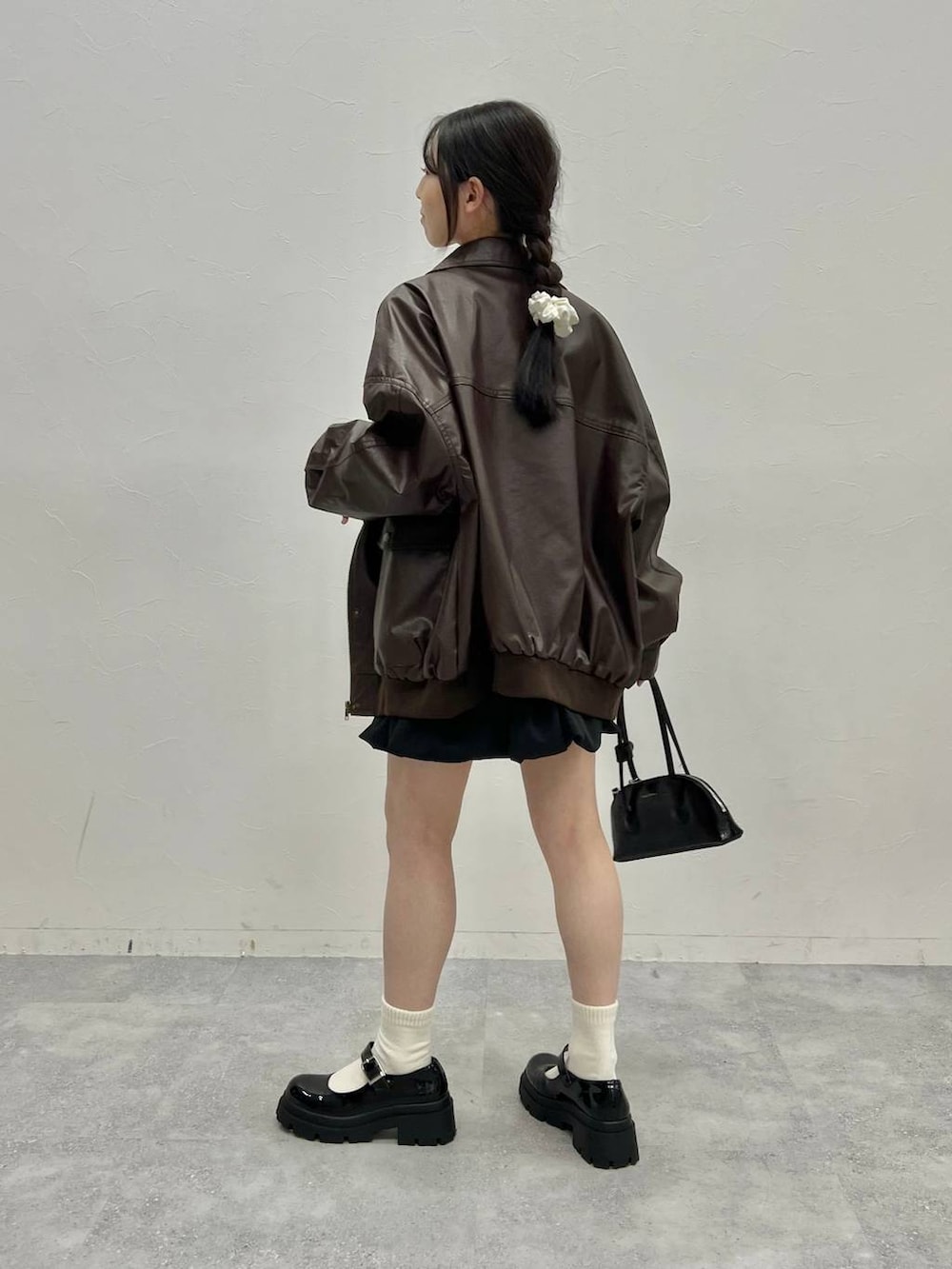 ブラウン系のブルゾン、グレー系のスウェット、ブラック系のハンドバッグを着用したレディースの冬コーディネートの3枚目の写真