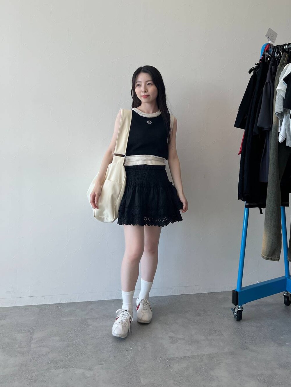 ブラック系のスカート、ブラック系のベスト、ベージュ系のショルダーバッグを着用したレディースの春コーディネートの6枚目の写真