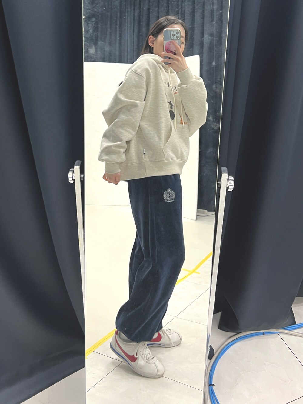 ブルー系のスウェットパンツ、ホワイト系のスニーカー、ベージュ系のパーカーを着用したレディースの冬コーディネートの2枚目の写真