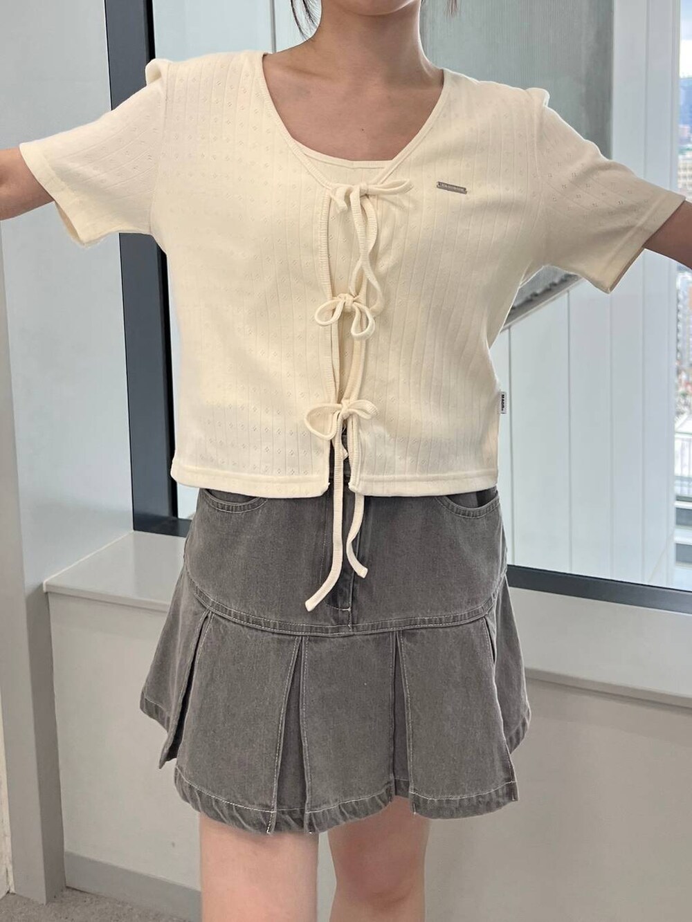 ベージュ系のカーディガン/ボレロ、グレー系のデニムスカートを着用したレディースの夏コーディネートの4枚目の写真