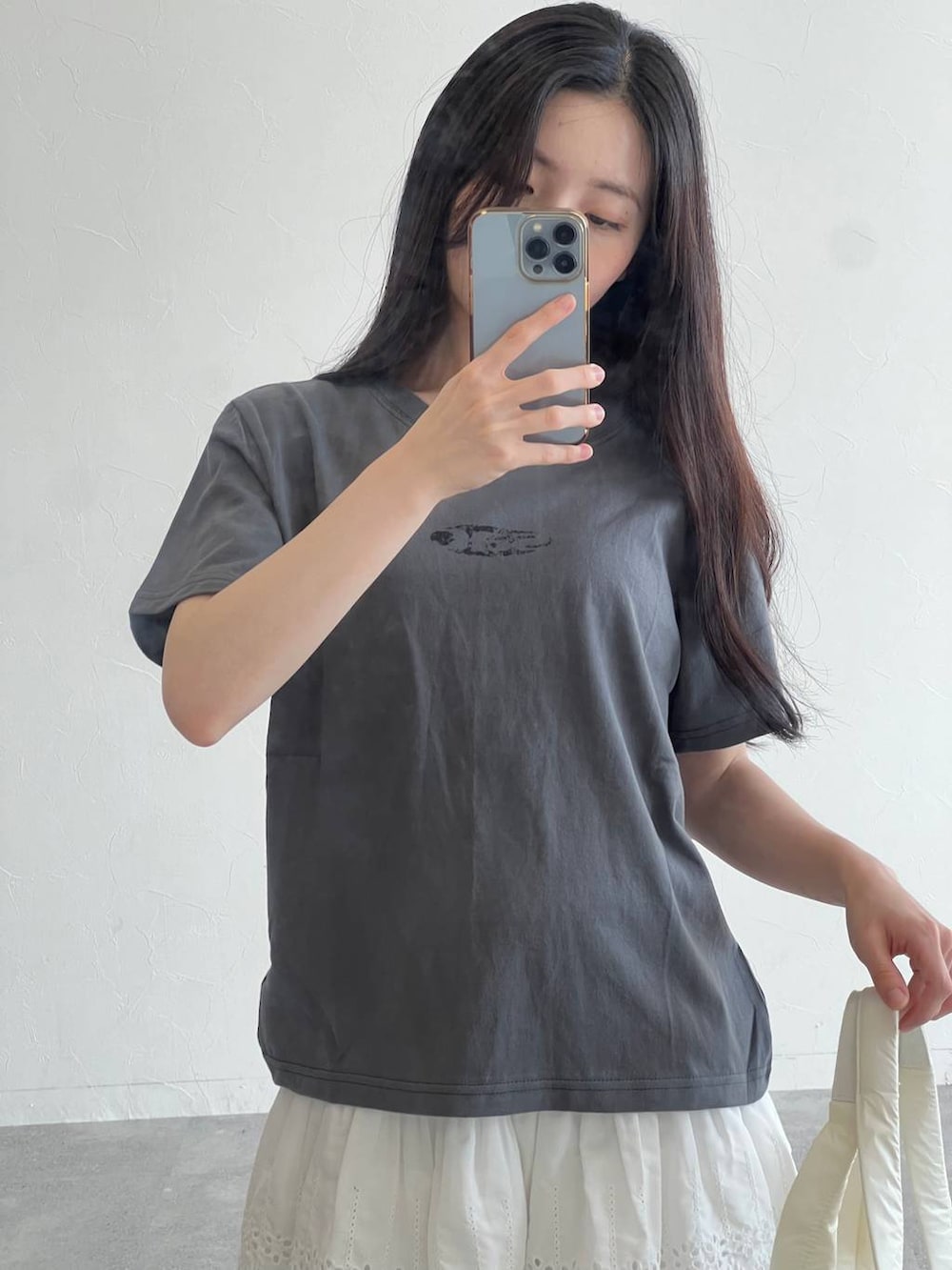 ホワイト系のスカート、ホワイト系のボストンバッグ、グレー系のTシャツ/カットソーを着用したレディースの夏コーディネートの3枚目の写真