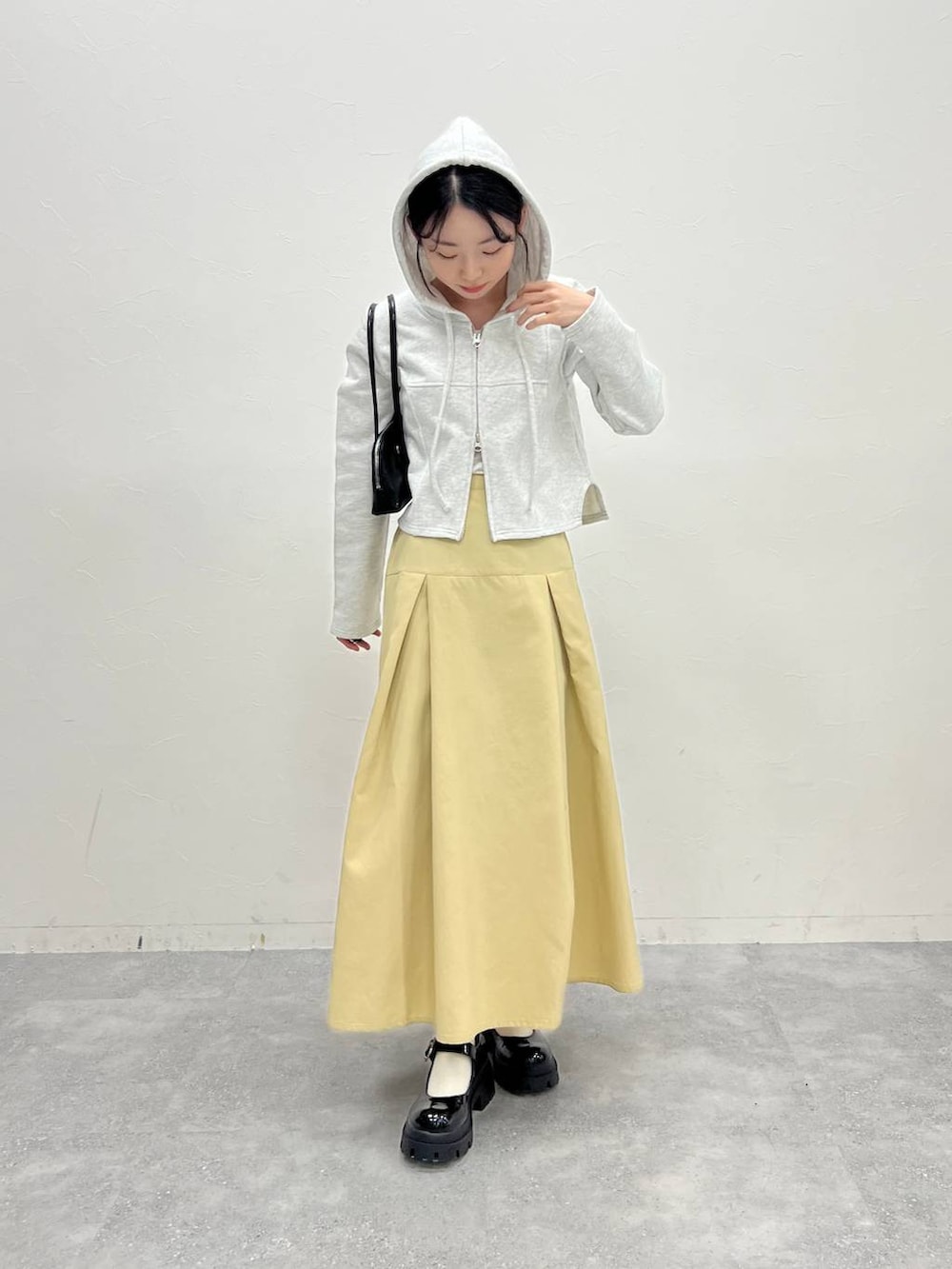 グレー系のスウェット、ベージュ系のスカート、ブラック系のハンドバッグを着用したレディースの冬コーディネートの2枚目の写真