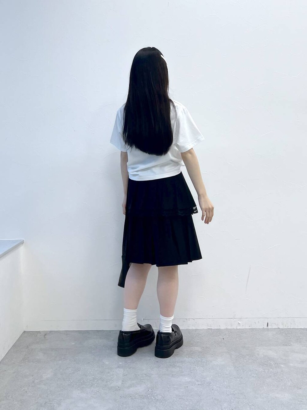 ブラック系のスカート、ホワイト系のTシャツ/カットソー、ブラック系のハンドバッグを着用したレディースの夏コーディネートの4枚目の写真
